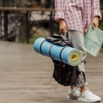 Personne tenant un tapis de randonnée bleu et une carte, prête pour une excursion en plein air.