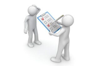 Deux personnages stylisés : l’un pose des questions à l’autre à l’aide d’un grand questionnaire à cocher.
