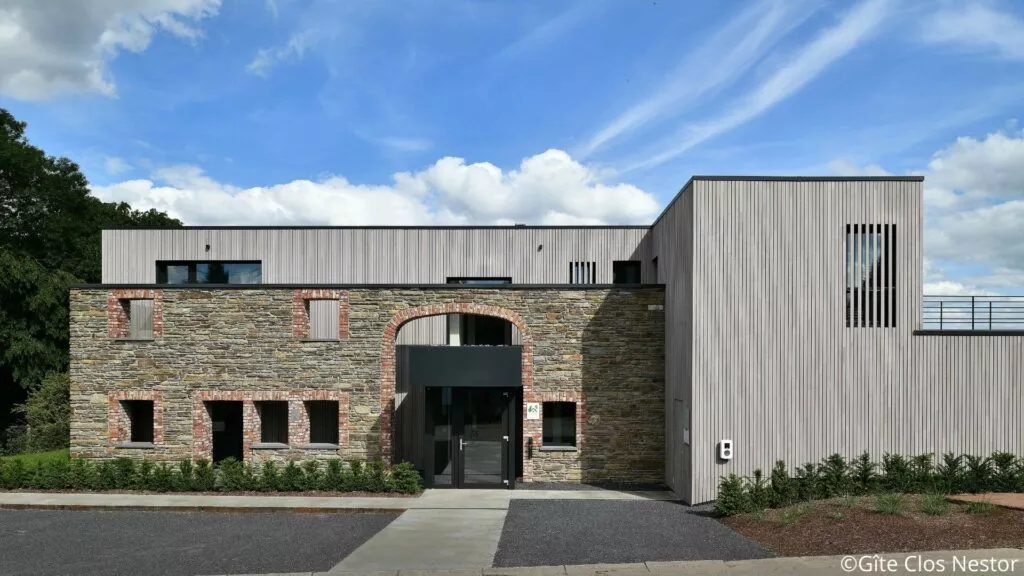 Façade moderne du gîte Le Clos Nestor à Xhoffraix, combinant pierre et bois, avec une entrée accessible aux personnes à mobilité réduite.